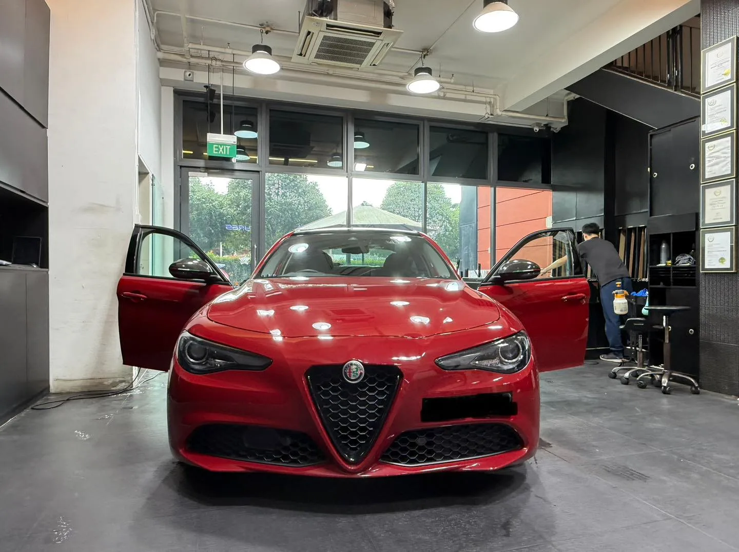 Red Alfa Romeo Giulia with doors open during window film installation at Infratint Singapore