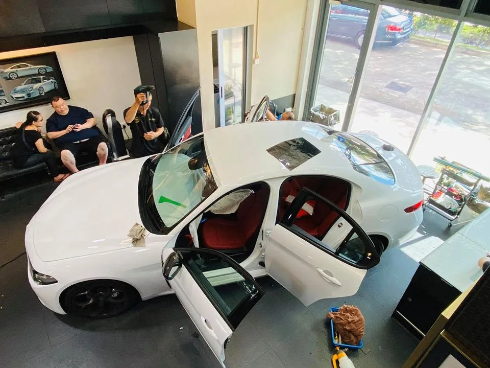 White Alfa Romeo Giulia with doors open during window film install at Infratint Singapore