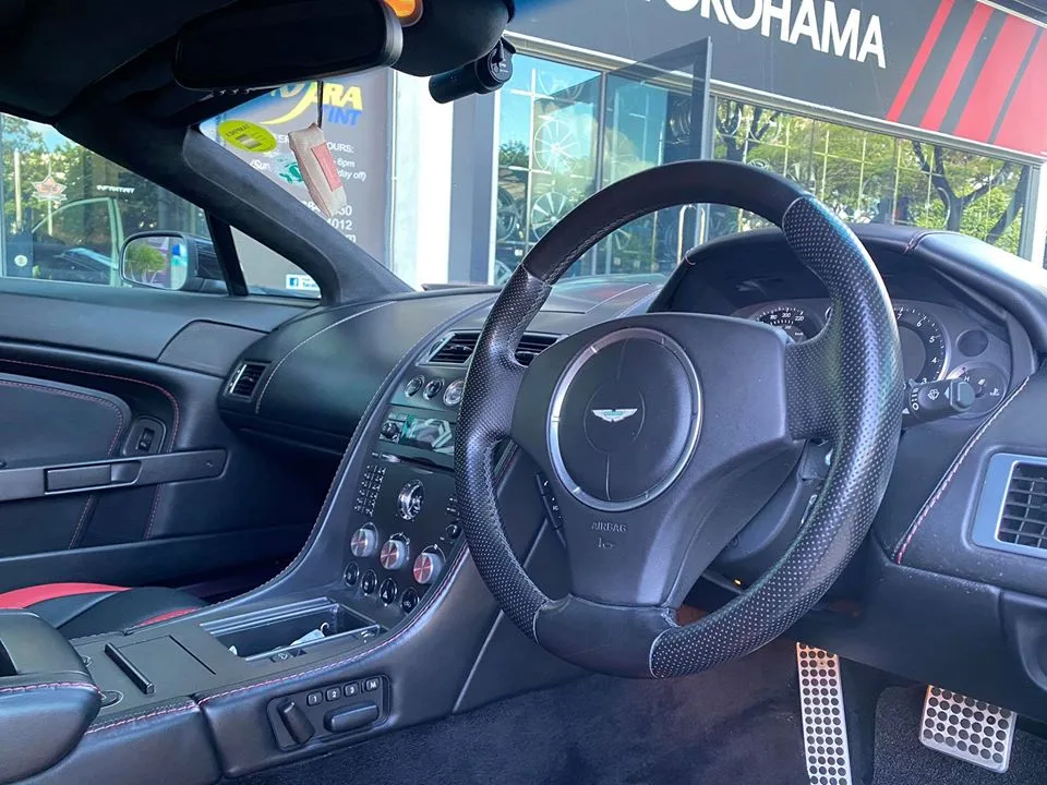 Aston Martin interior and steering wheel viewed through tinted glass at Infratint Singapore