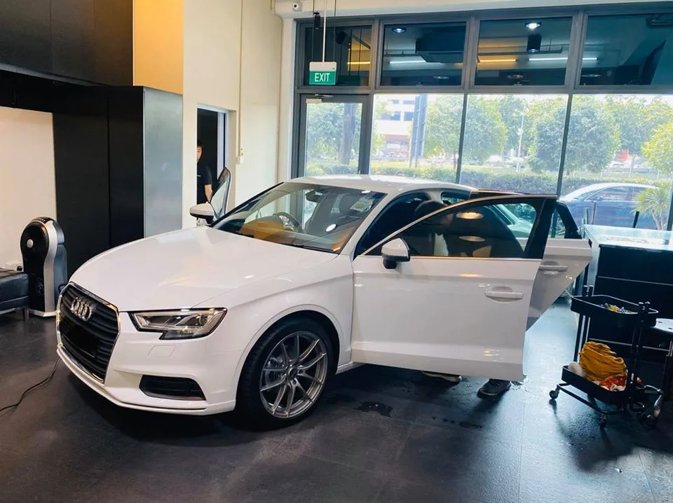 Front three-quarter of a white Audi A3 with doors open at Infratint Singapore window tinting bay