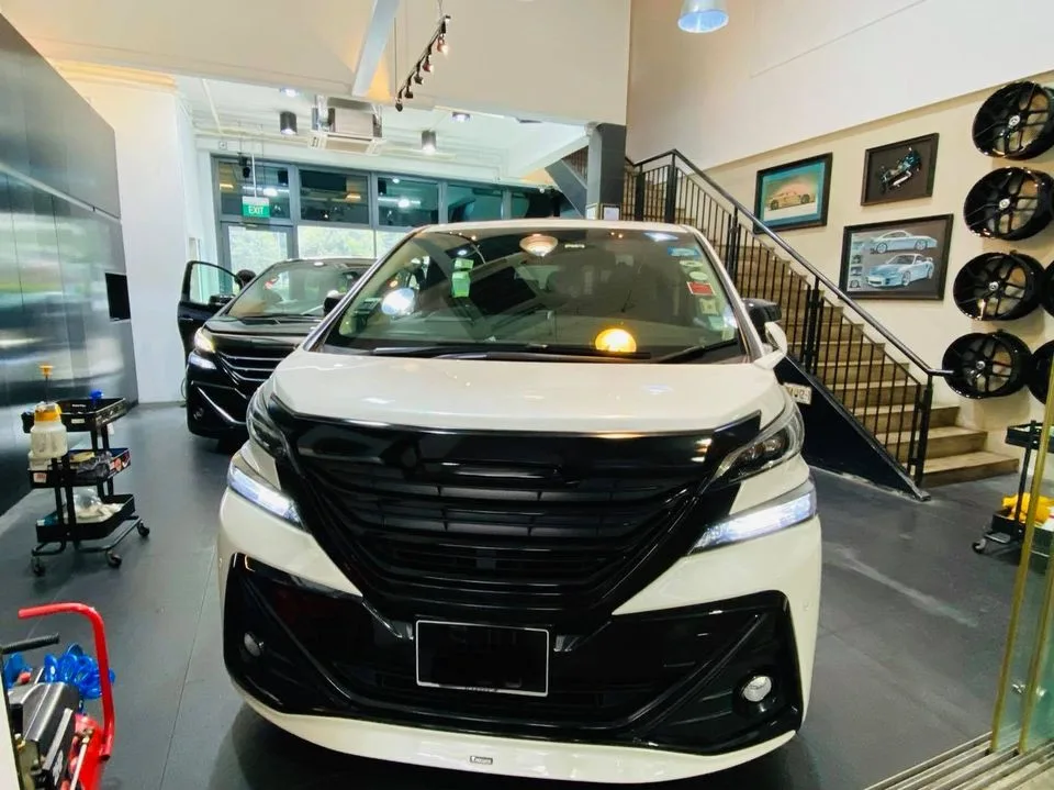 White Toyota MPV at Infratint Singapore for window tinting beside a wheel display wall