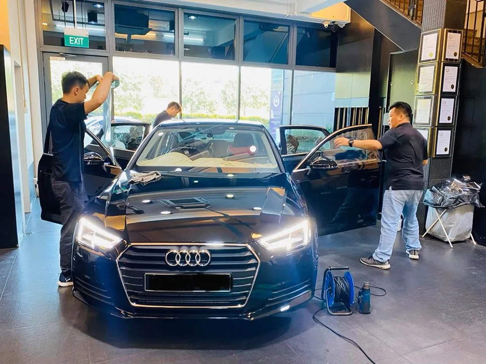 Dark blue Audi sedan with doors open getting window film at Infratint Singapore