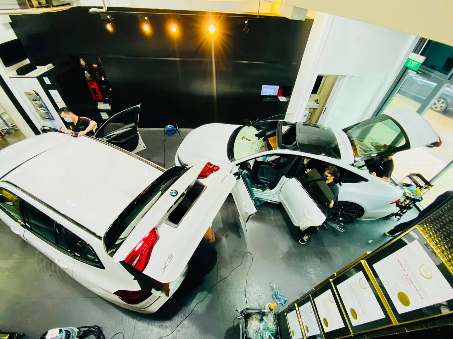 White BMW vehicles with doors open during window tinting at Infratint Singapore