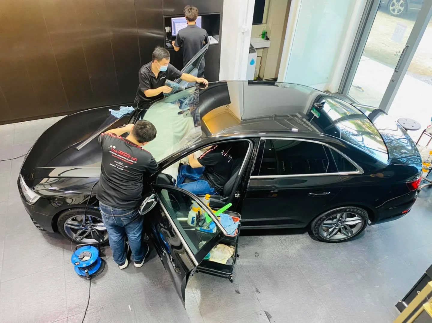 Overhead view of a black Audi sedan during window film installation at Infratint Singapore