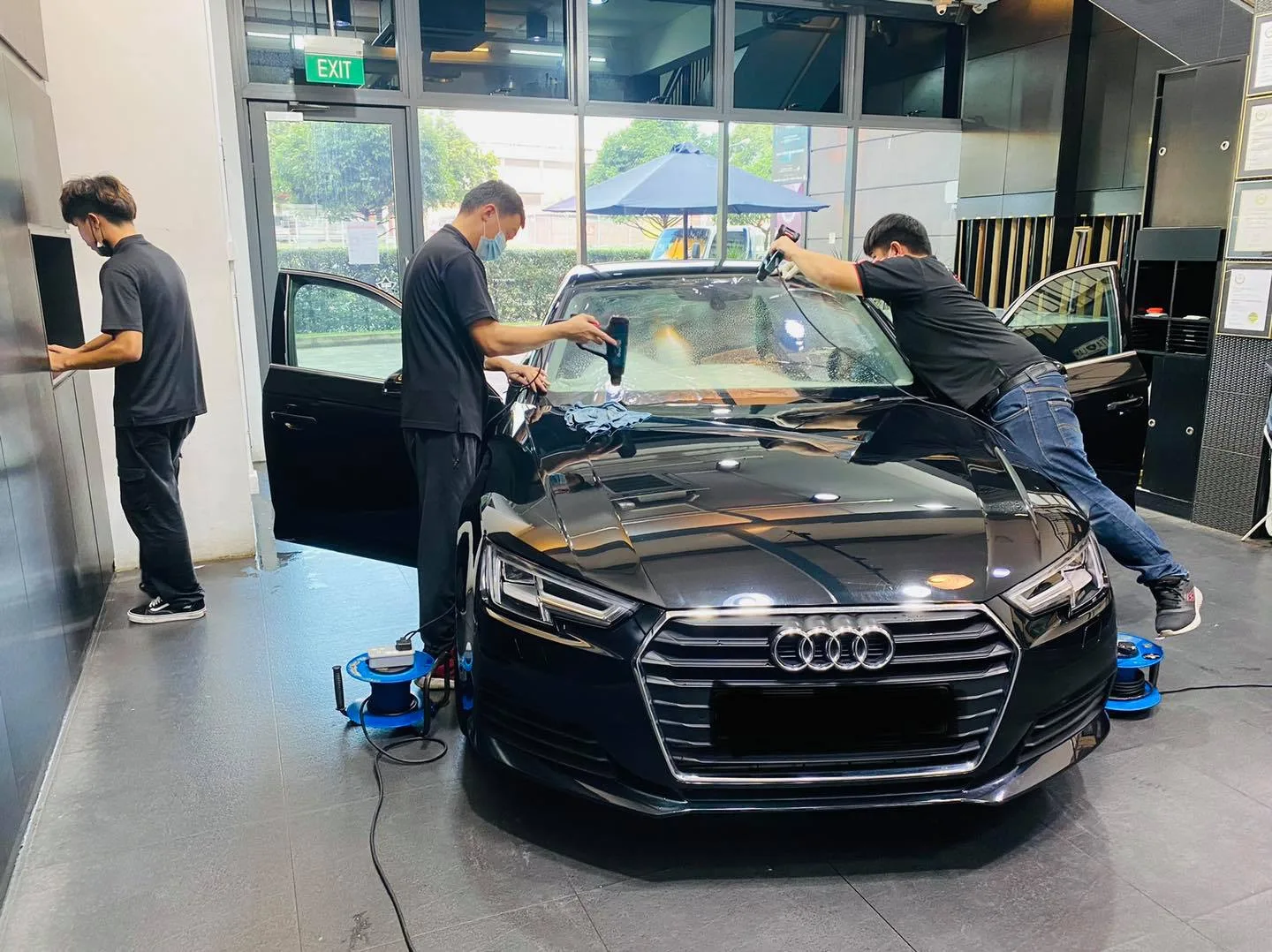 Installers fitting window film to a black Audi sedan at Infratint Singapore
