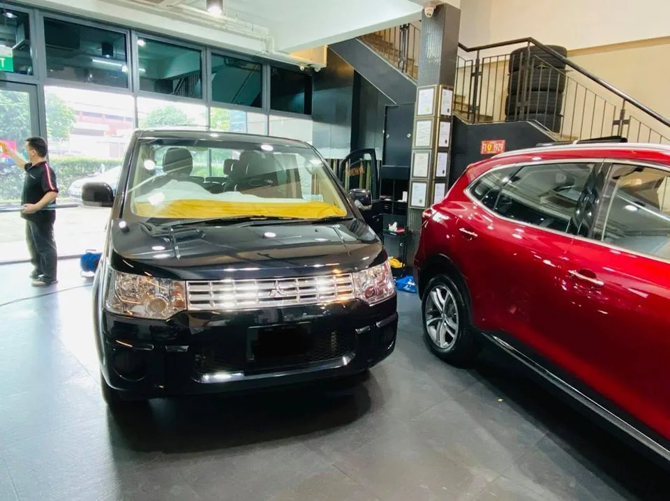 Black Mitsubishi Delica MPV and a red MG SUV at Infratint Singapore for window film