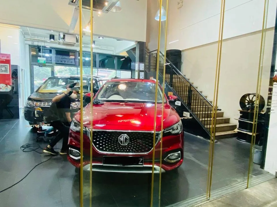 Red MG HS SUV beside a black van during window tinting at Infratint Singapore