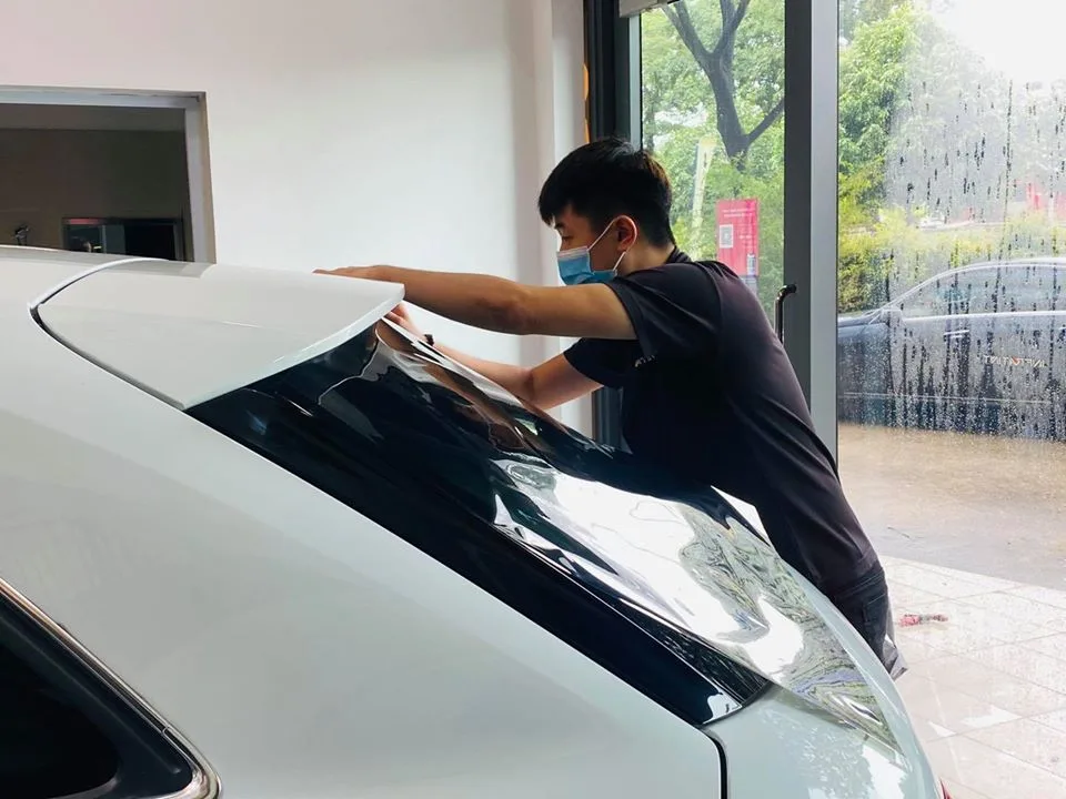 Technician fitting tint film to the rear windscreen of an Audi Q3 at Infratint Singapore