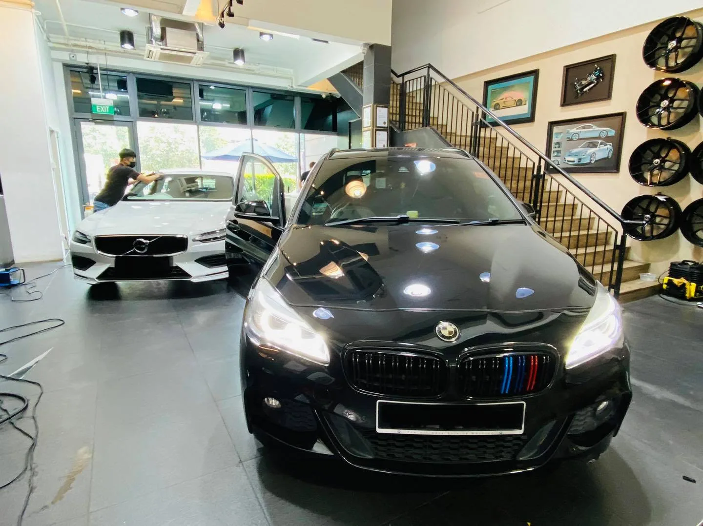 Black BMW front view with a white Volvo behind at Infratint Singapore window tinting bay