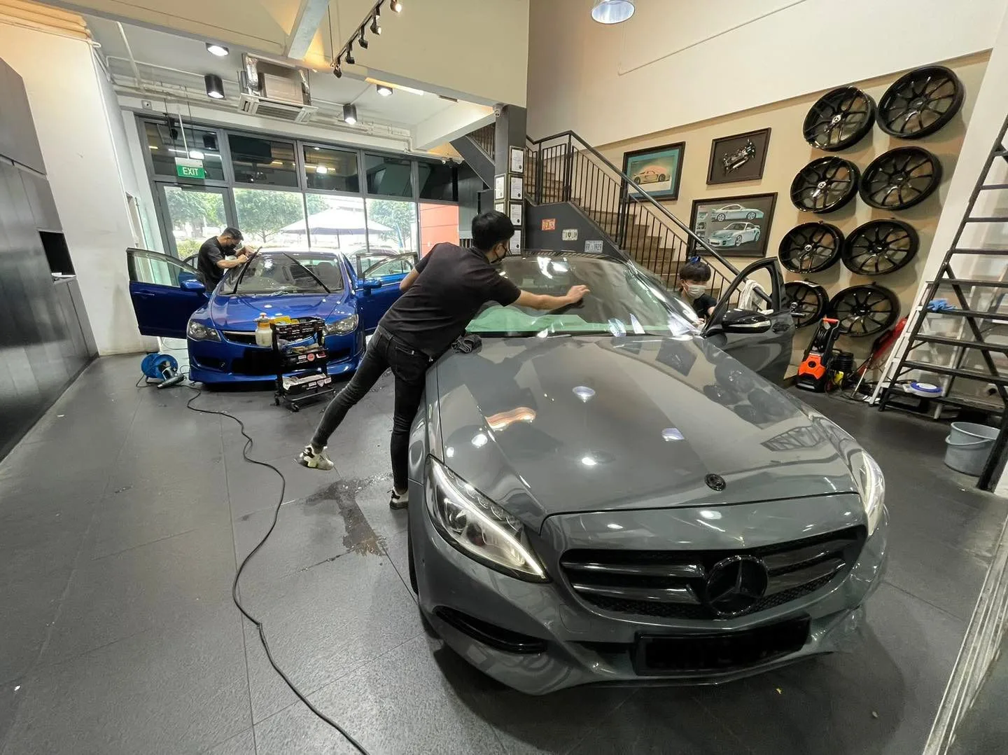 Technician applying window film to a grey Mercedes-Benz C-Class at Infratint Singapore
