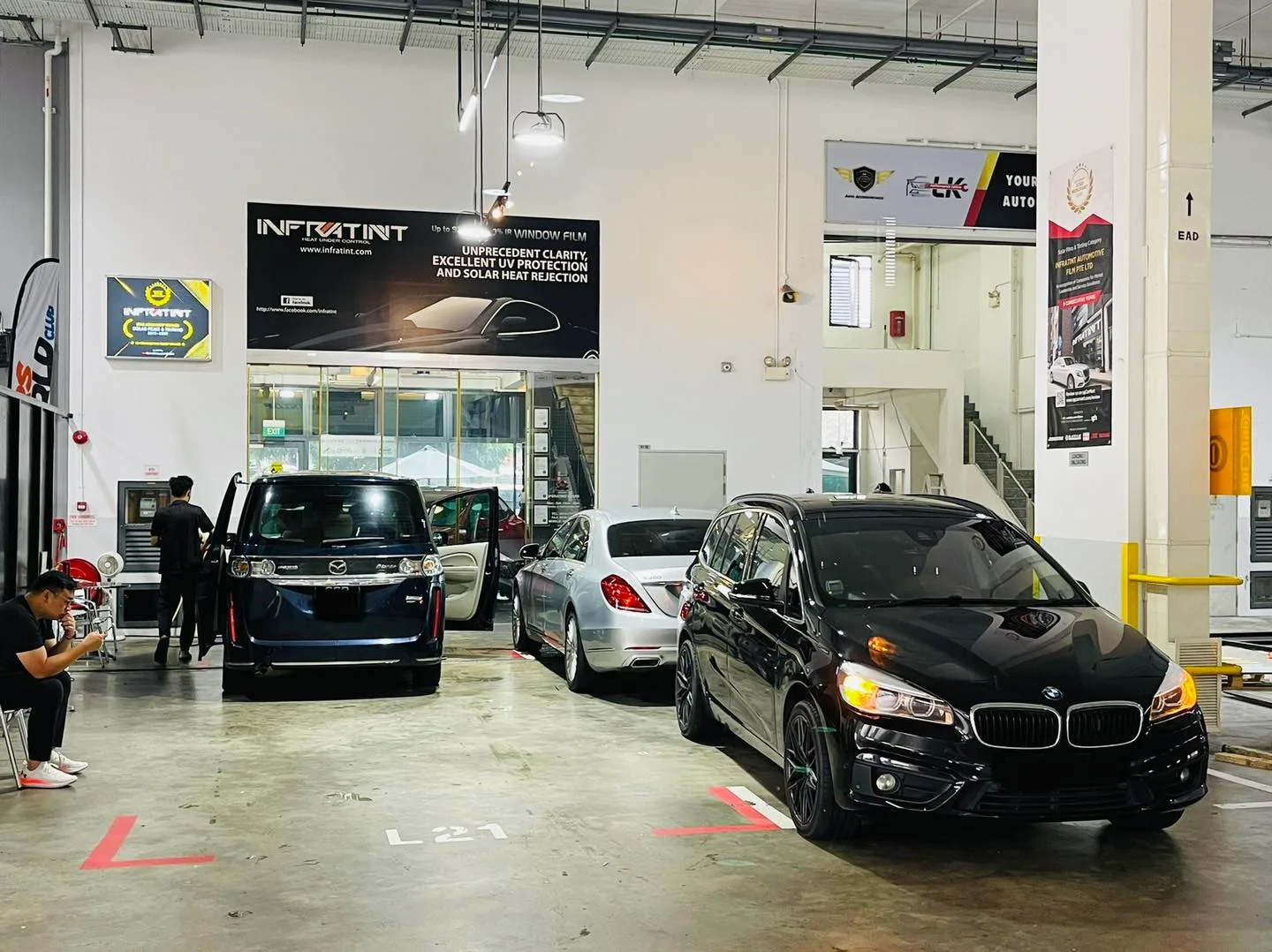 Black BMW with a silver Mercedes-Benz and a van at the Infratint Singapore workshop