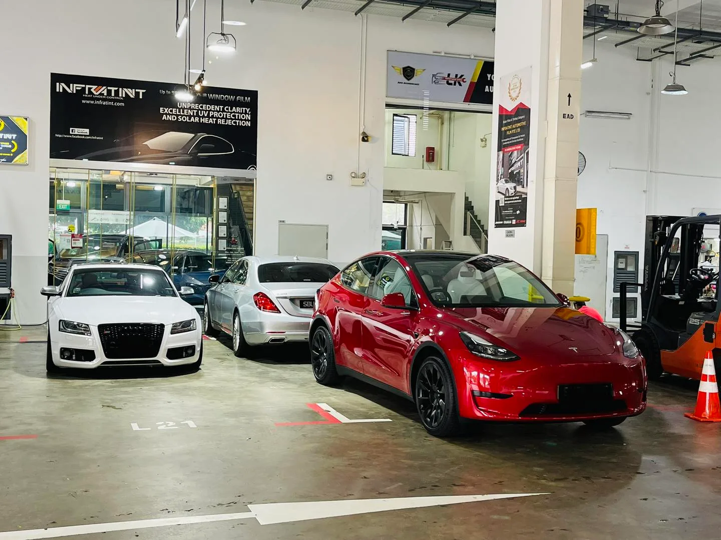 Red Tesla Model Y with a white Audi and silver Mercedes-Benz at the Infratint Singapore workshop