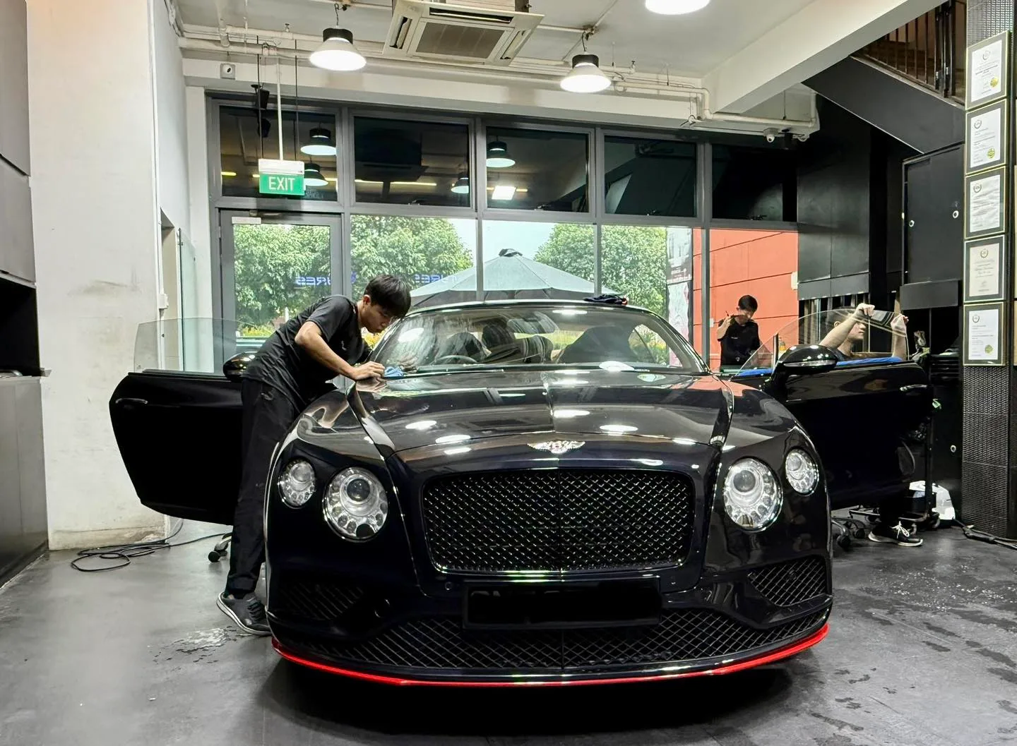 Technician fitting window film to a black Bentley GT windscreen at Infratint Singapore