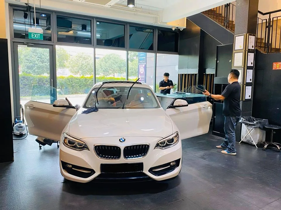White BMW coupe with doors open during window tinting at Infratint Singapore