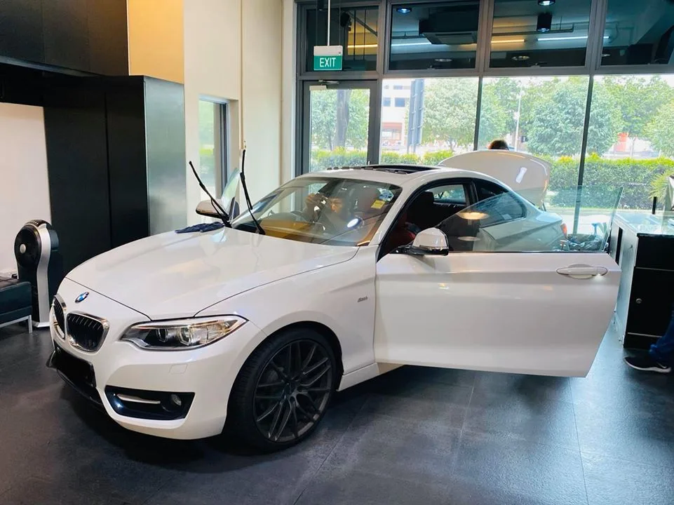 Front three-quarter of a white BMW coupe mid window-tint install at Infratint Singapore