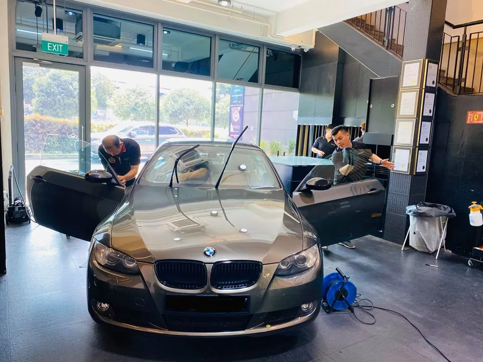 Grey two-door BMW with doors open during window tinting at Infratint Singapore