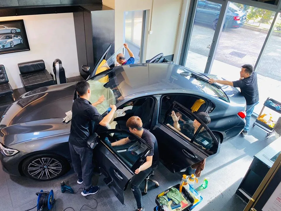 Overhead view of technicians tinting a grey BMW 3 Series at Infratint Singapore