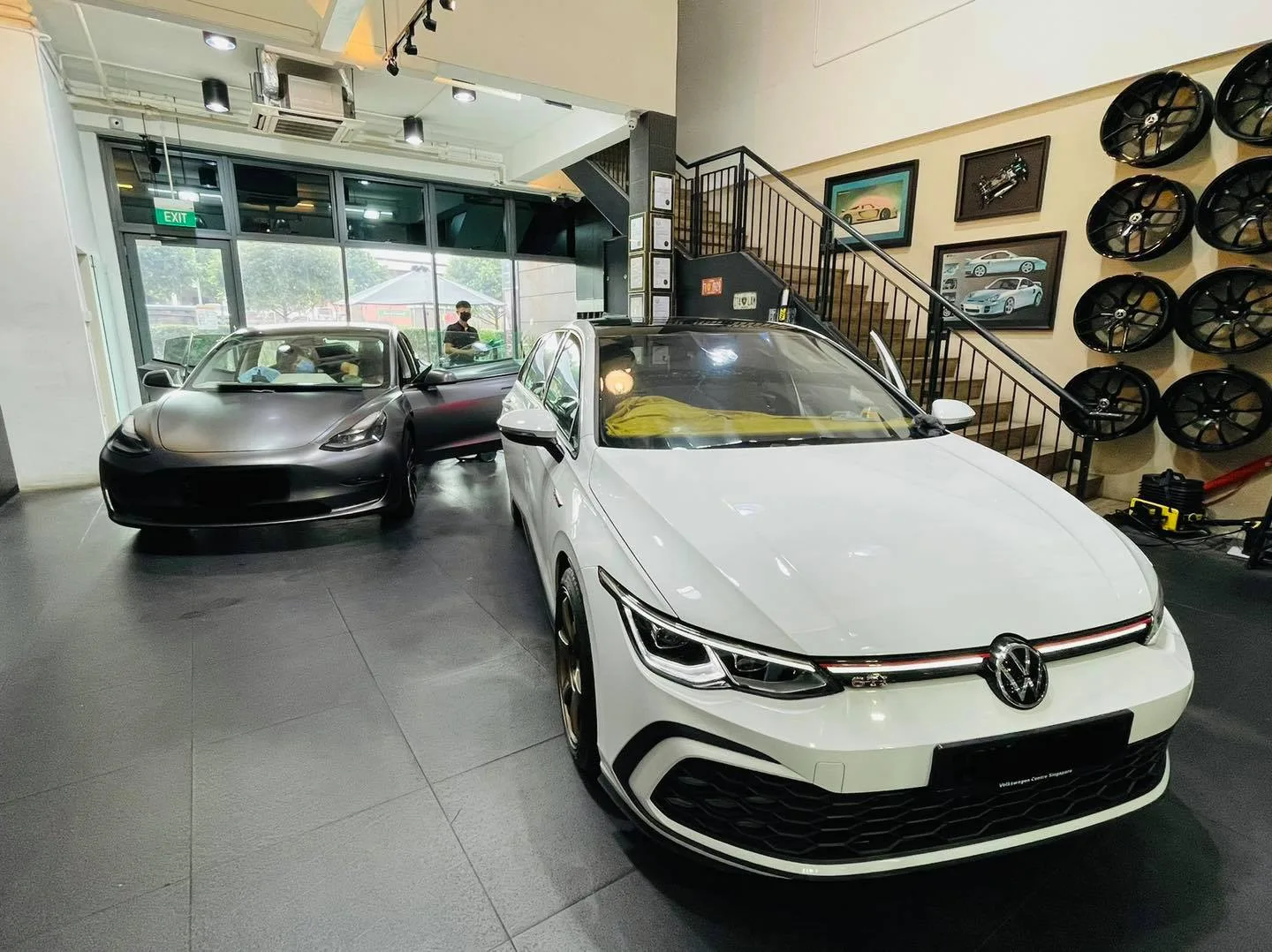 White Volkswagen Golf and dark Tesla Model 3 inside the Infratint Singapore showroom
