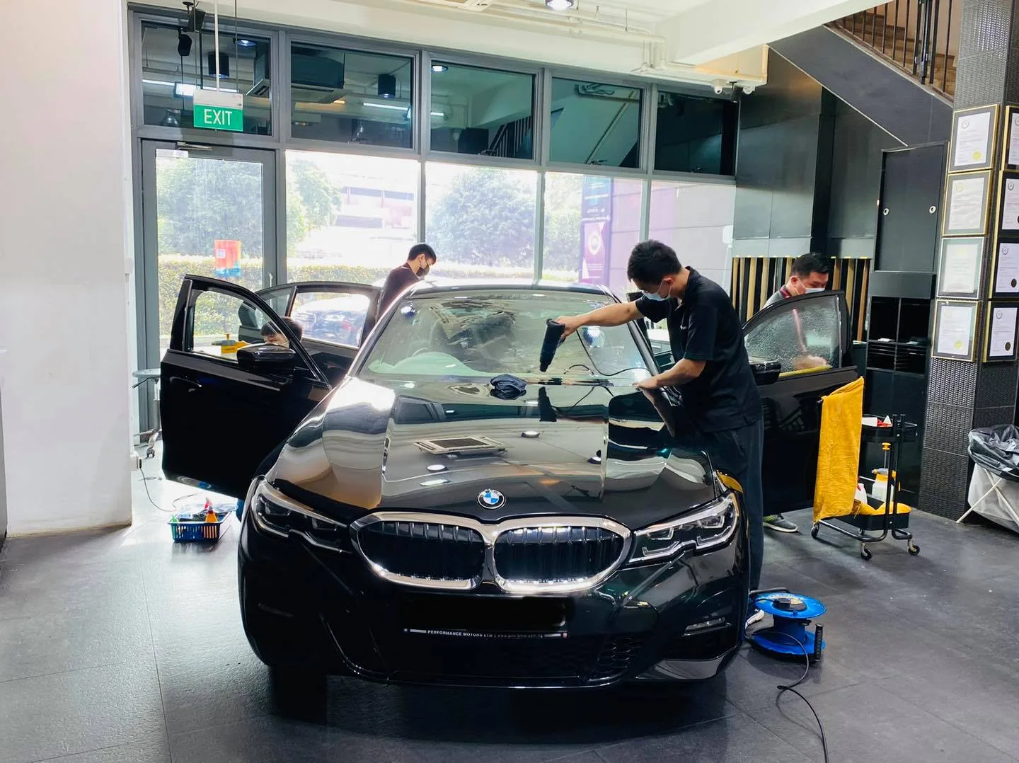 Installers applying window film to a black BMW 3 Series at Infratint Singapore