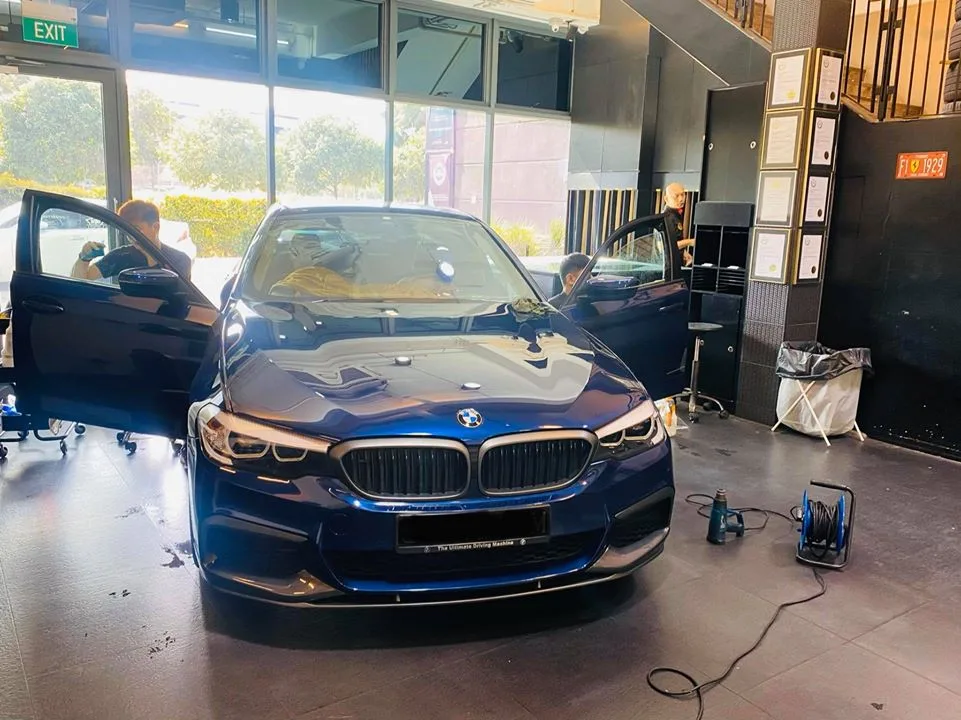 Blue BMW 5 Series sedan front view during window tinting at Infratint Singapore