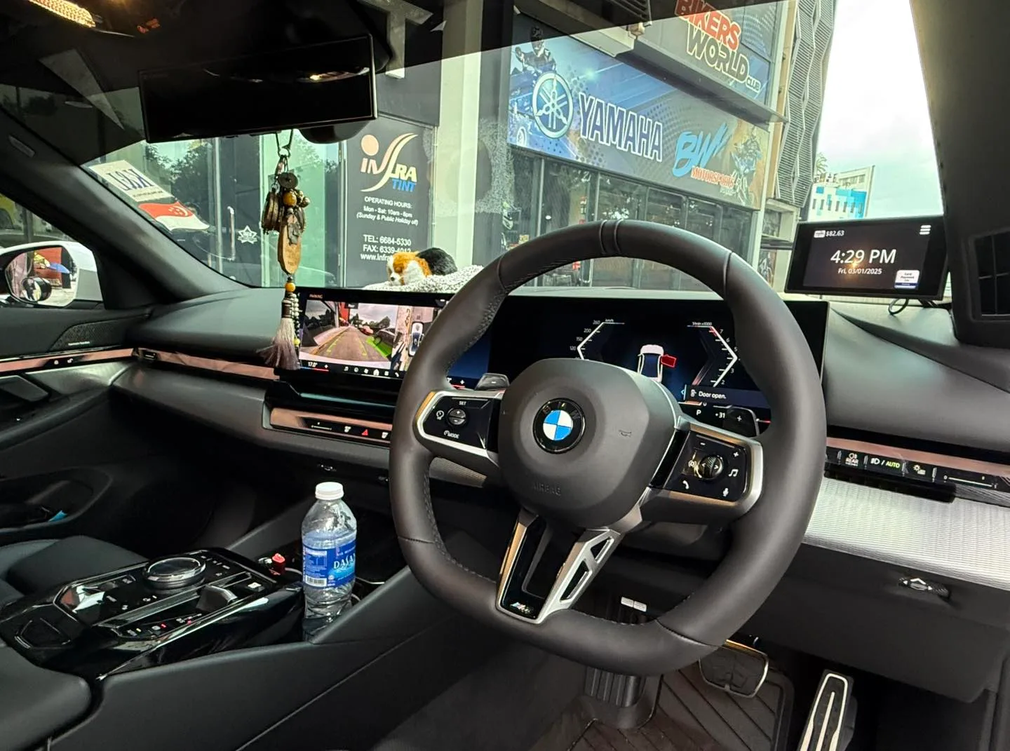 BMW 520i interior steering wheel and curved display seen through tinted glass at Infratint Singapore