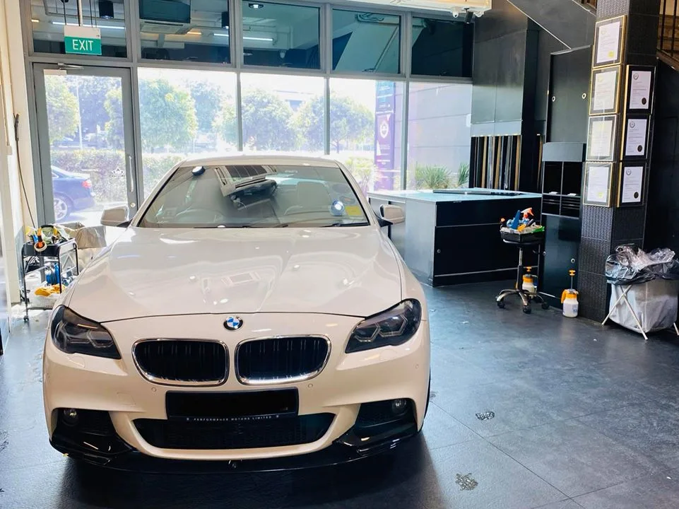White BMW 5 Series sedan being prepped for window film at Infratint Singapore