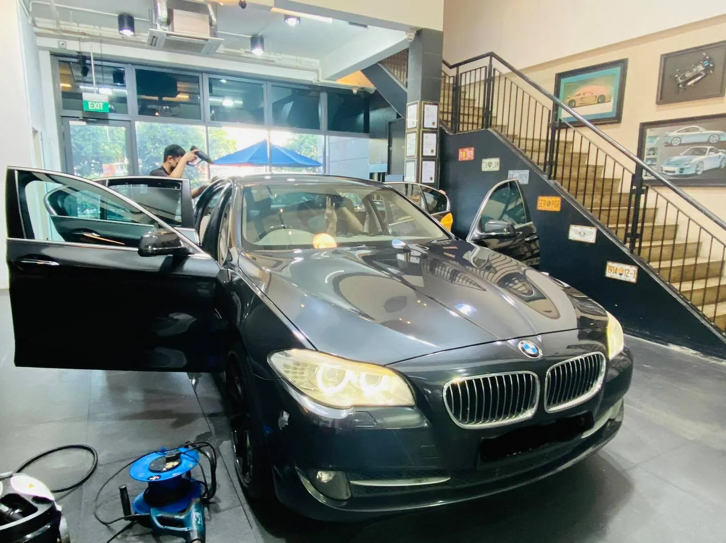 Black BMW 5 Series with doors open during window tinting at Infratint Singapore