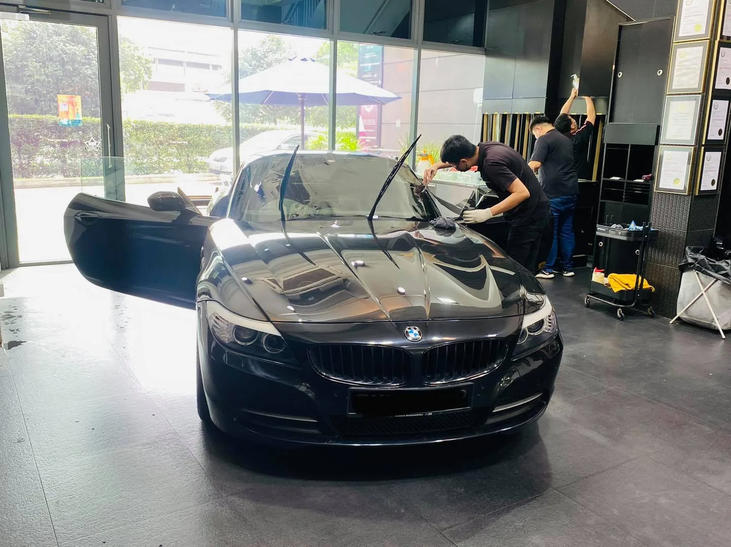 Technicians tinting a black BMW Z4 roadster at Infratint Singapore
