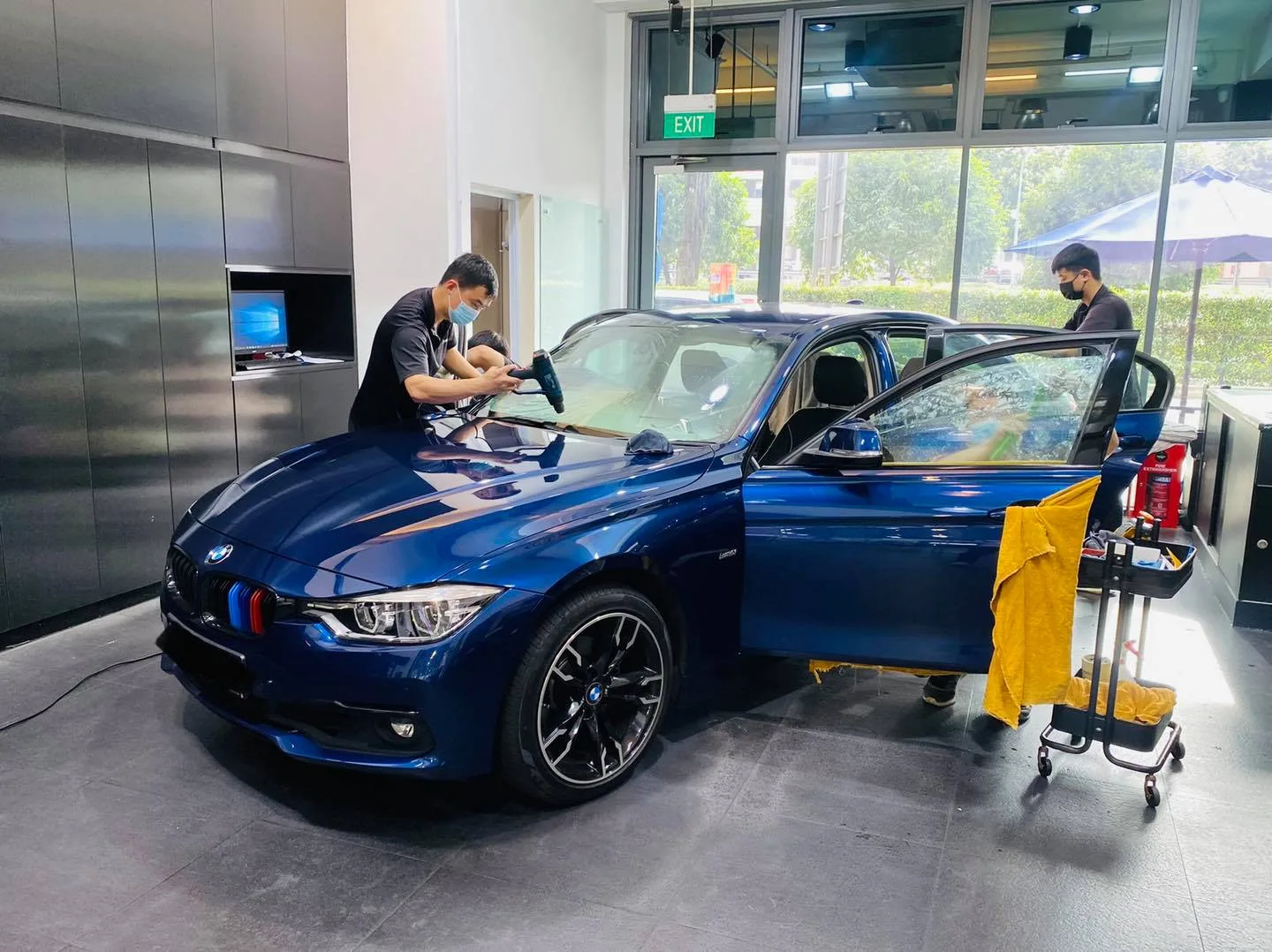 Blue BMW 3 Series with door open during window tinting at Infratint Singapore