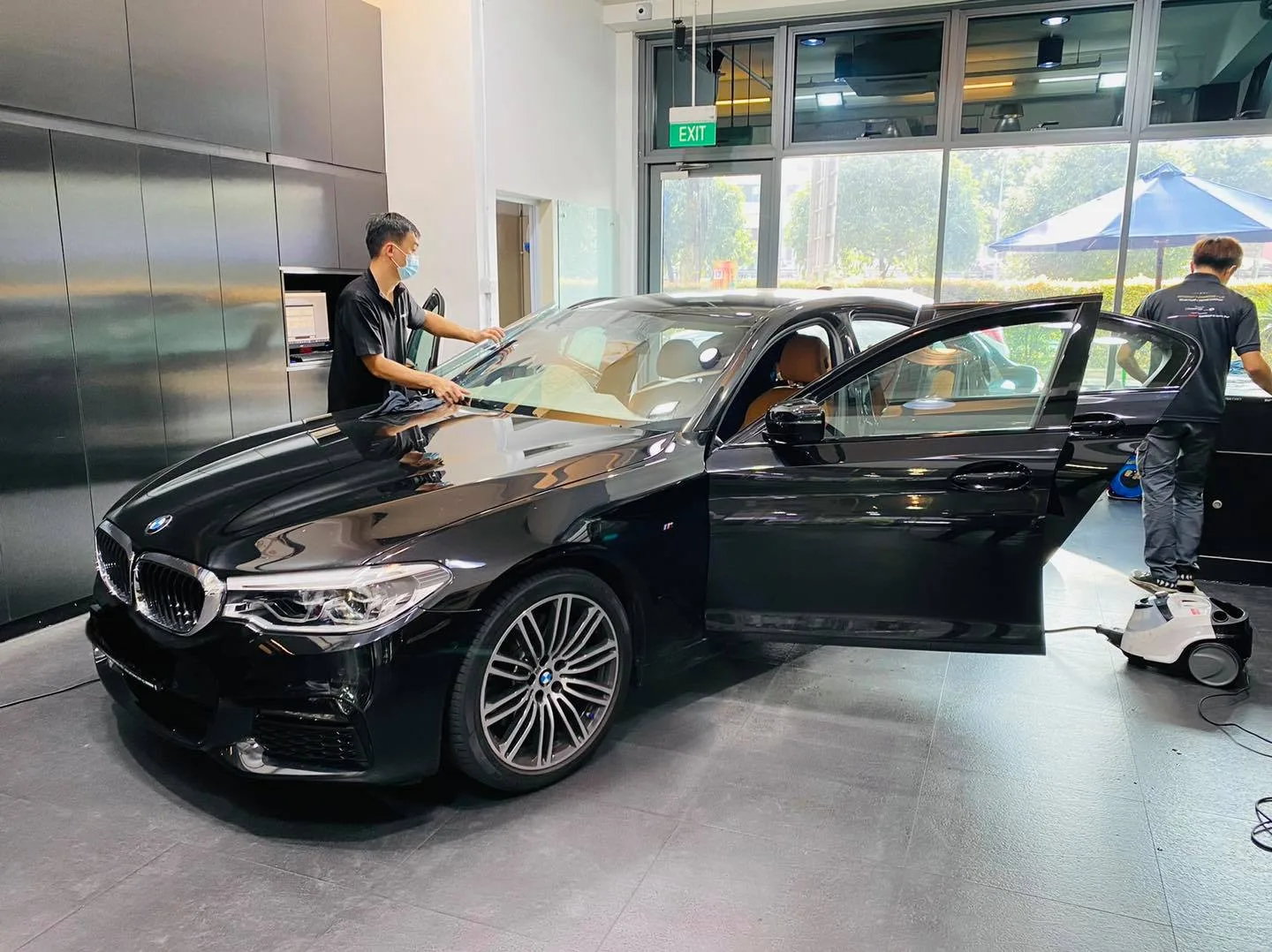 Side view of a black BMW 5 Series during window tinting at Infratint Singapore