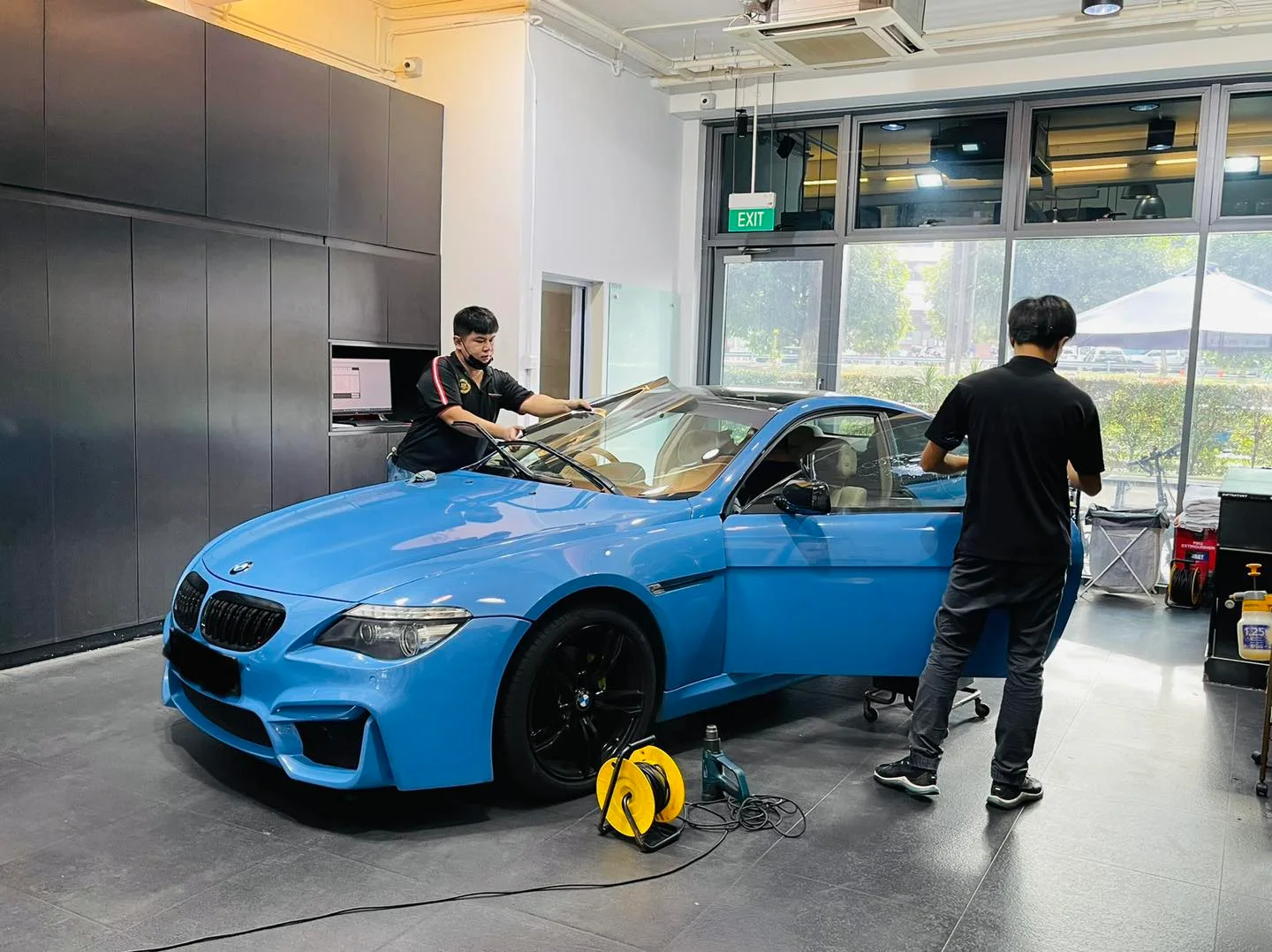 Light blue BMW coupe with black wheels during window film install at Infratint Singapore