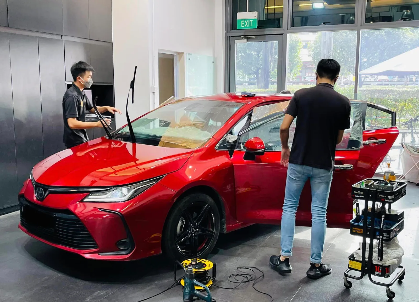 Front three-quarter view of a red Toyota sedan during window tinting at Infratint Singapore
