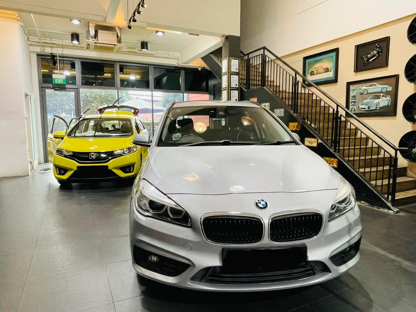 Silver BMW 2 Series and yellow Honda Fit inside the Infratint Singapore showroom