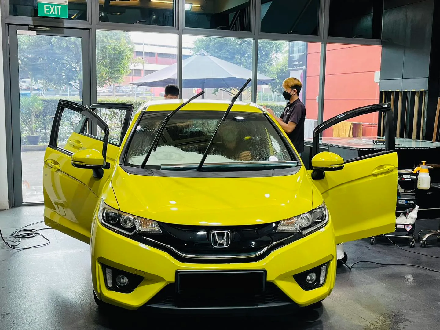 Yellow Honda Fit front view with doors open during window film install at Infratint Singapore
