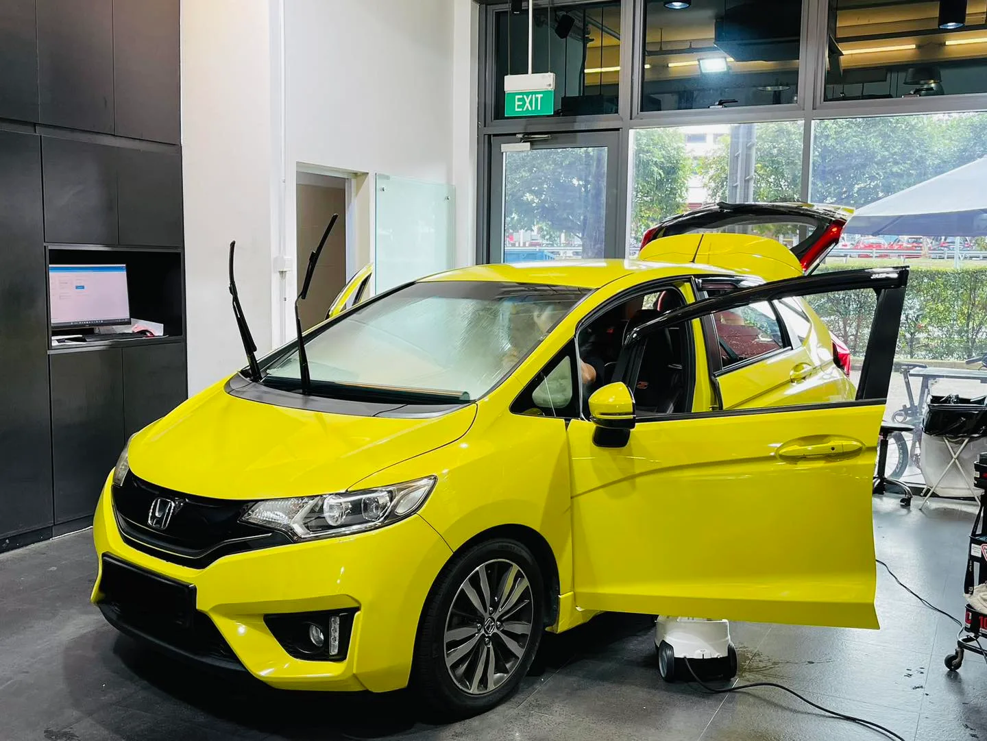 Yellow Honda Fit front three-quarter with doors open during tinting at Infratint Singapore