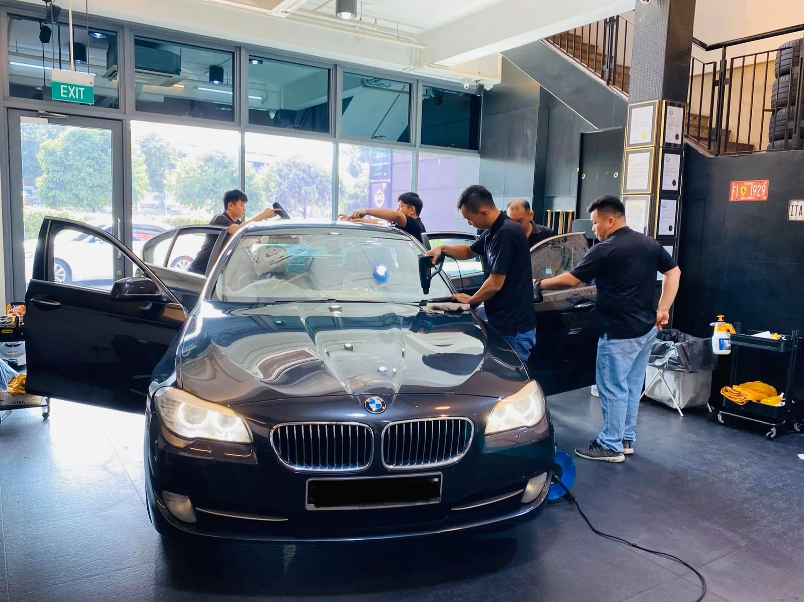 Black BMW 5 Series sedan surrounded by the team during window tinting at Infratint Singapore