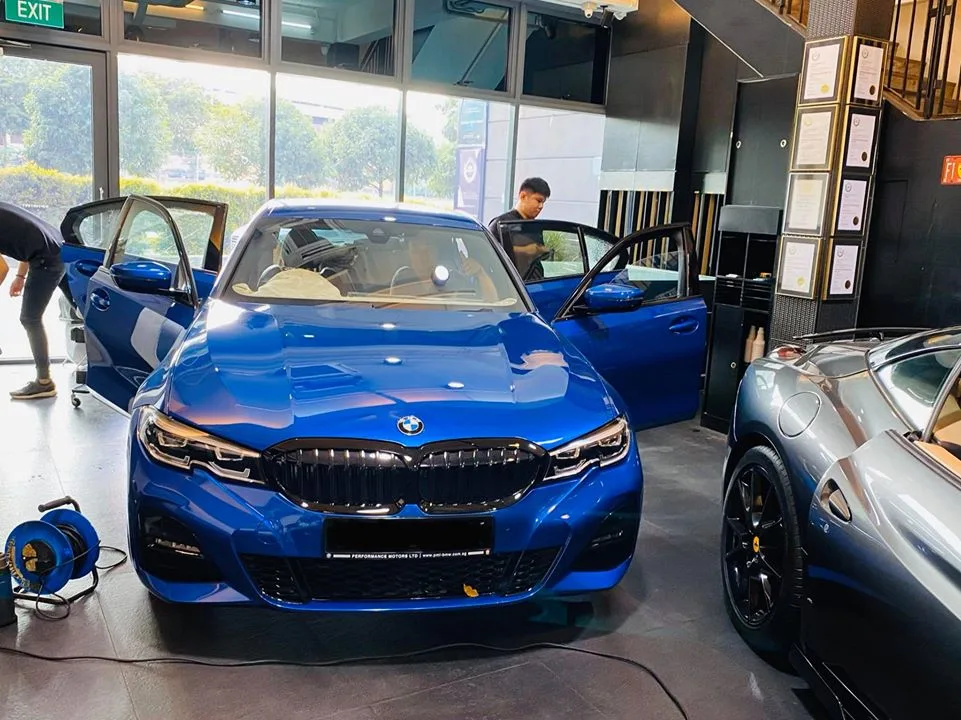 Blue BMW 3 Series beside a grey Ferrari convertible at Infratint Singapore