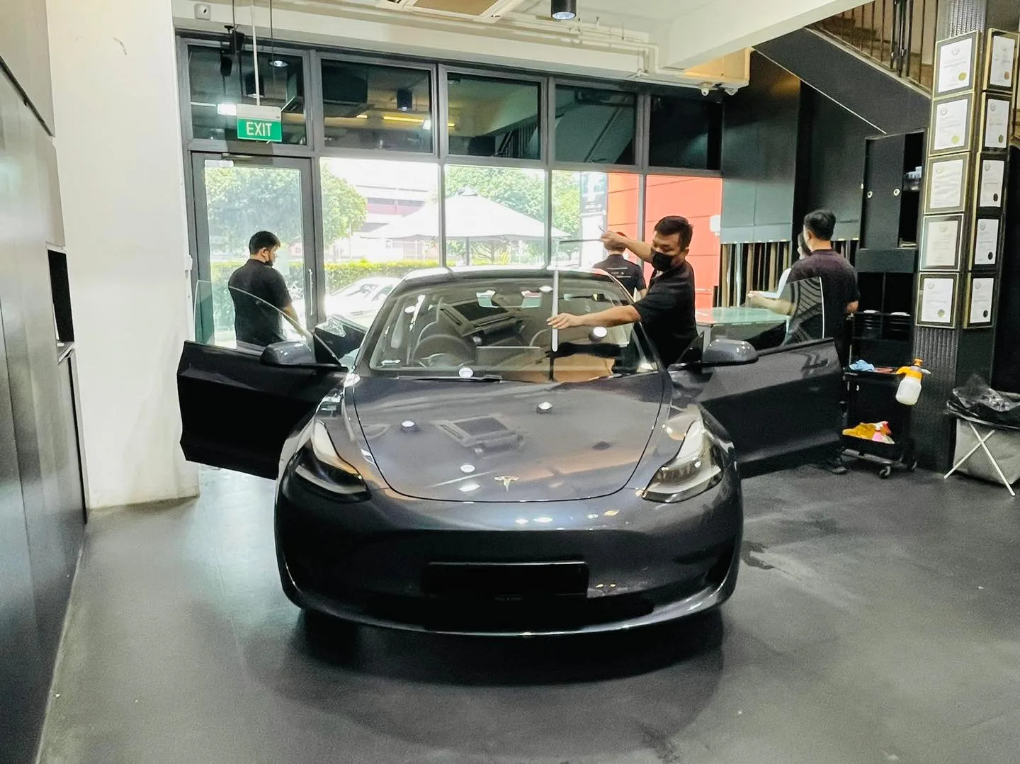 Grey Tesla Model 3 being tinted by three installers at Infratint Singapore