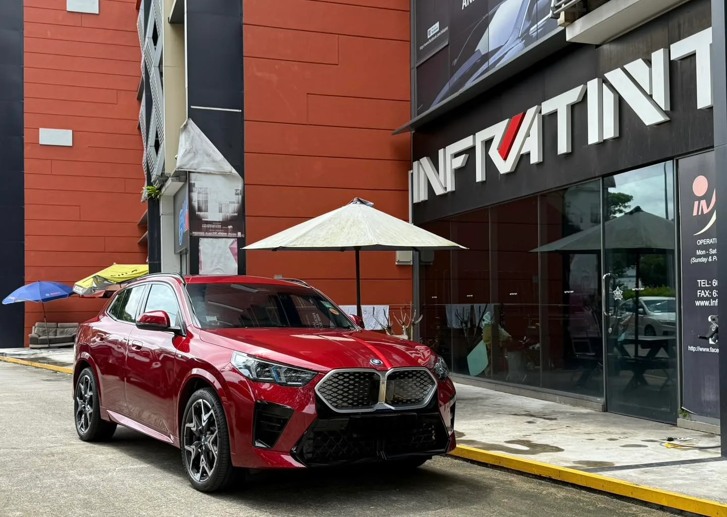 Red BMW iX2 front three-quarter view outside Infratint Singapore