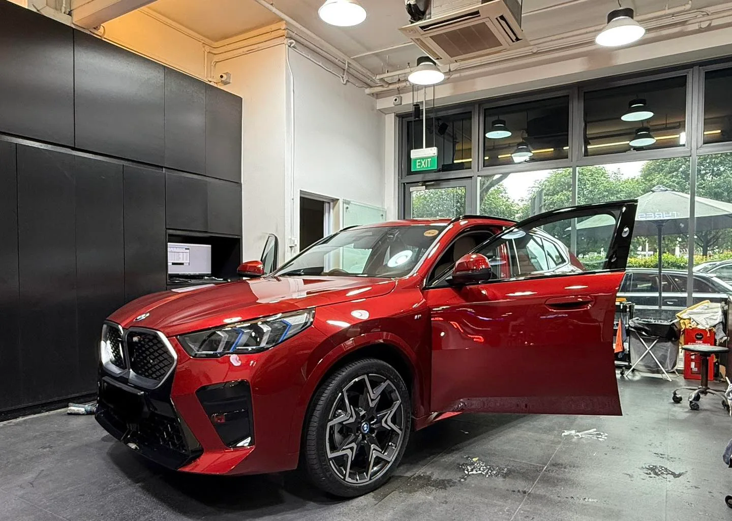 Red BMW iX2 front three-quarter view inside Infratint workshop during install