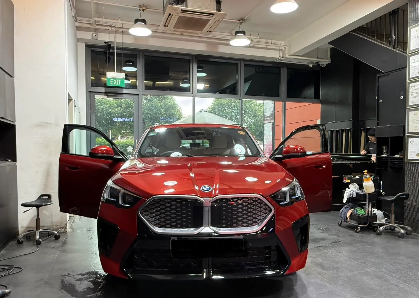 Red BMW iX2 with doors open during window film installation in Infratint workshop