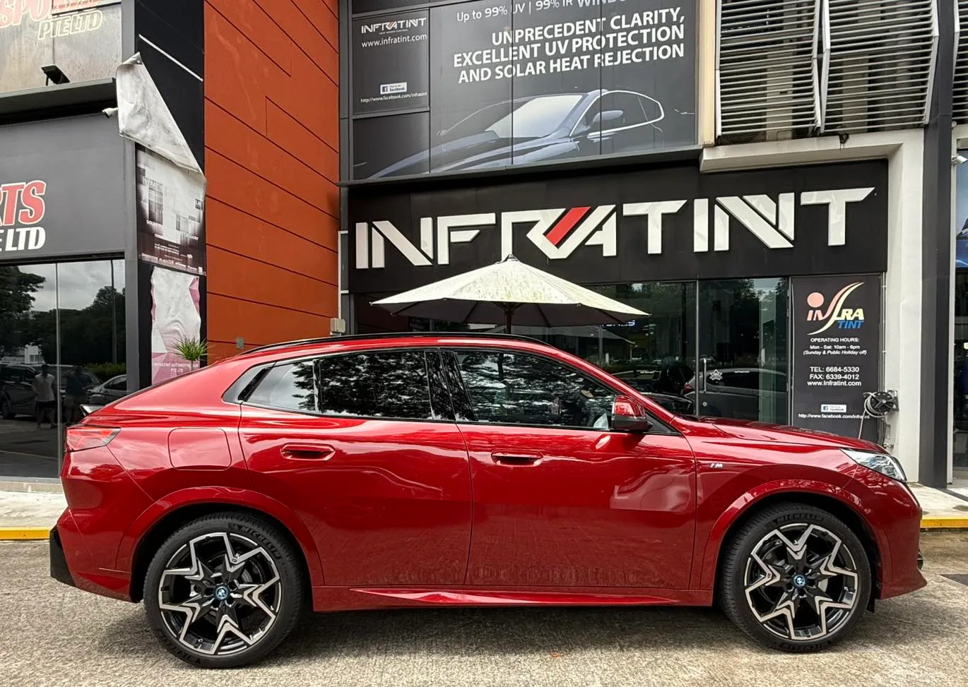 Red BMW iX2 side profile with tinted windows at Infratint Singapore