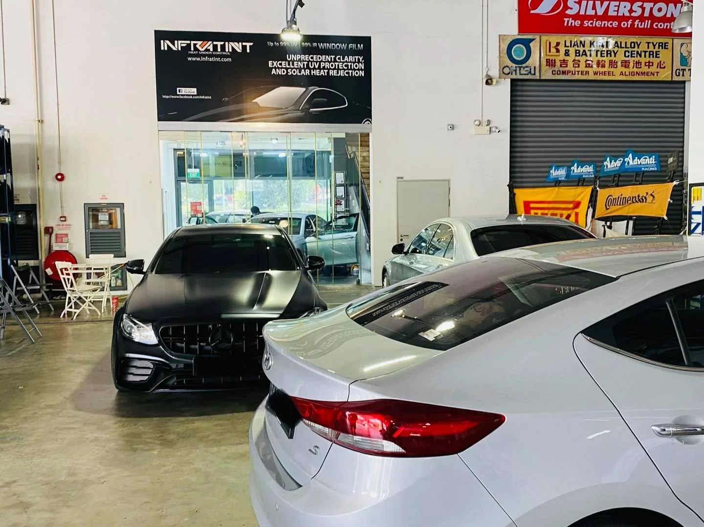 Black Mercedes-Benz coupe and silver sedan in the workshop at Infratint Singapore