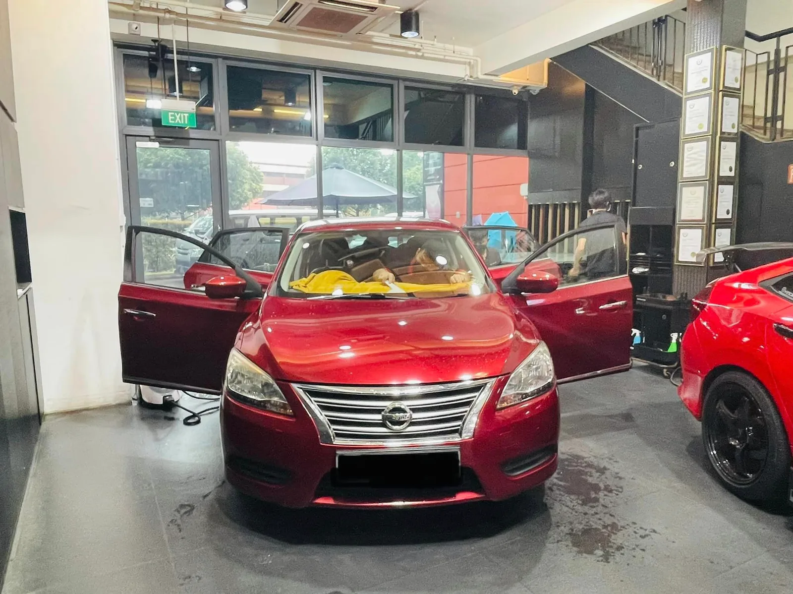 Red Nissan Sylphy with doors open being prepared for window film at Infratint Singapore