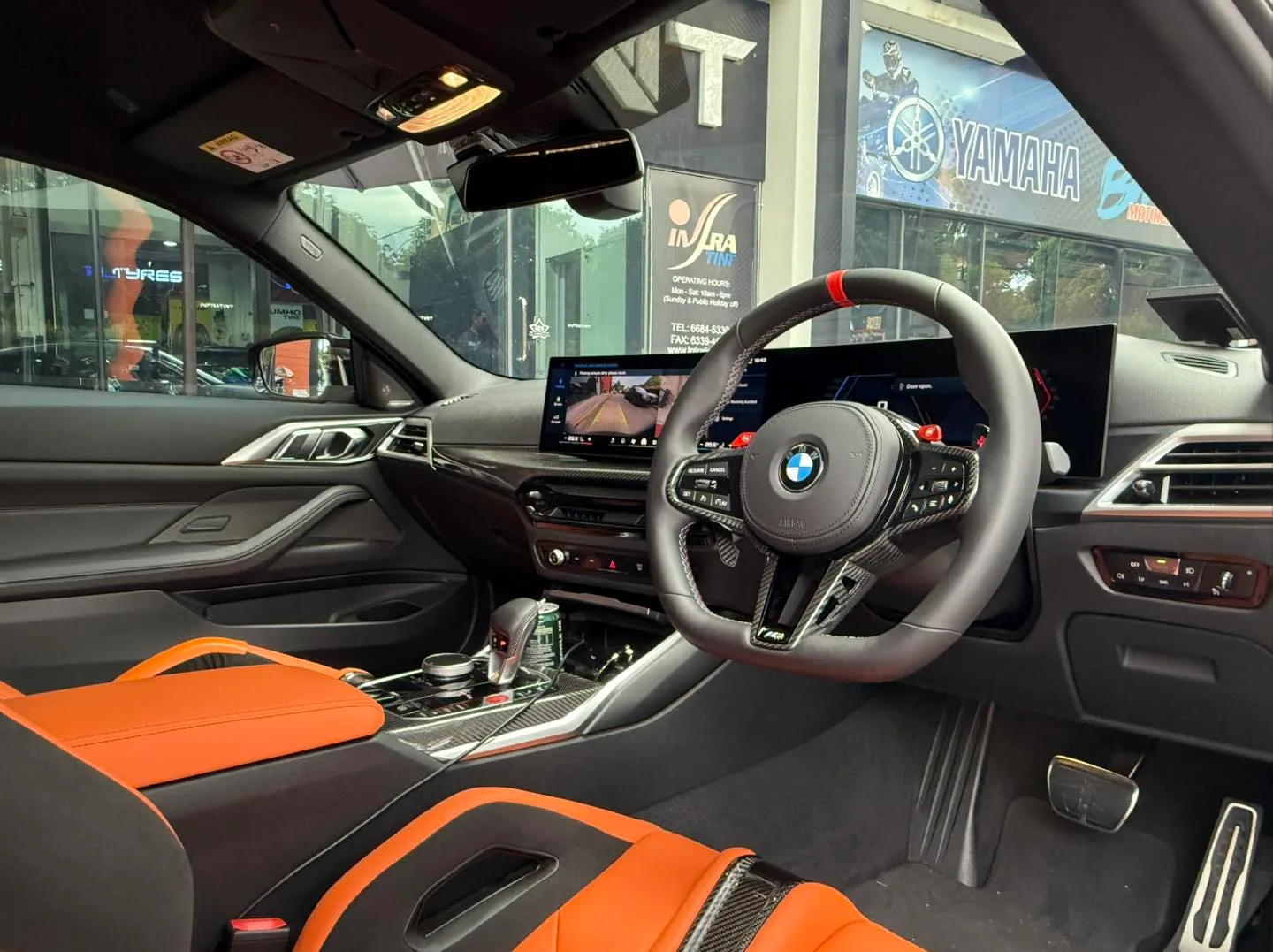 BMW M4 Competition interior with carbon M steering wheel, orange bucket seats and tinted windows