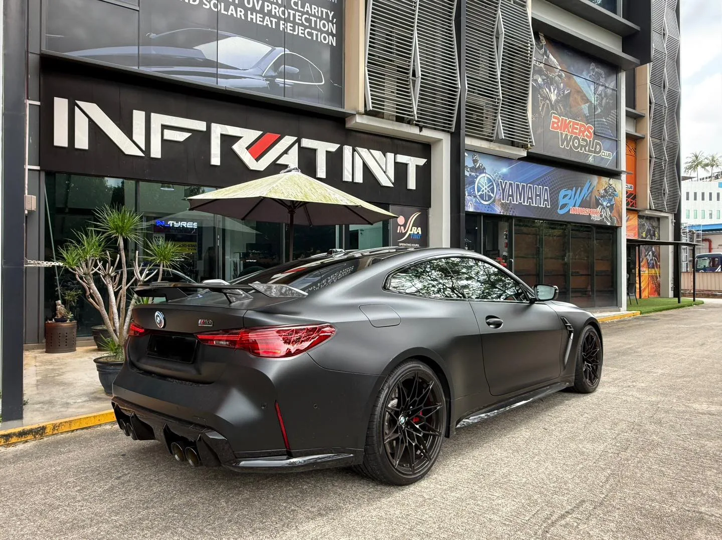 Matte grey BMW M4 Competition rear three-quarter with quad exhaust and tinted rear glass