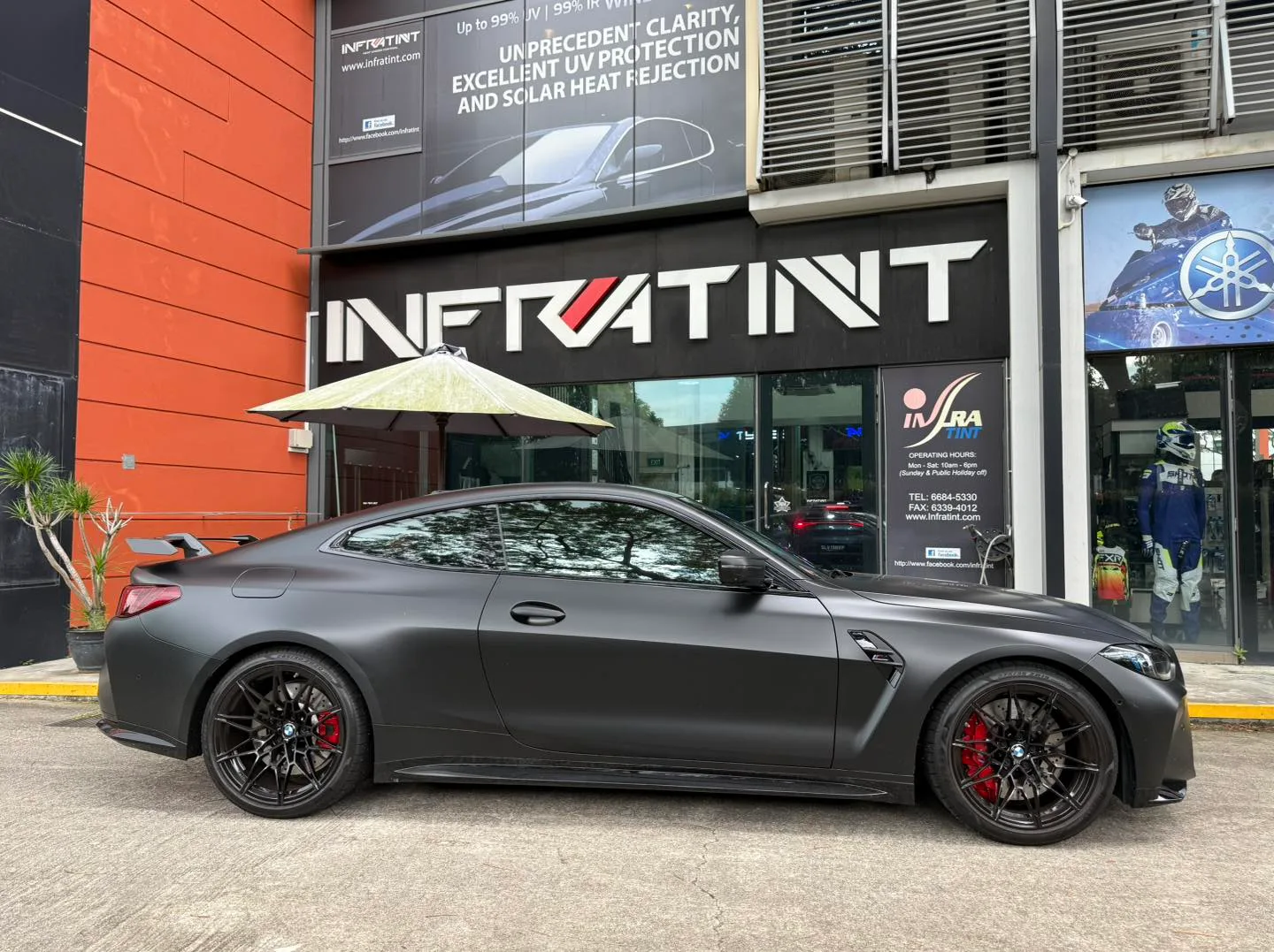 Matte grey BMW M4 Competition side profile with tinted windows and red brake calipers