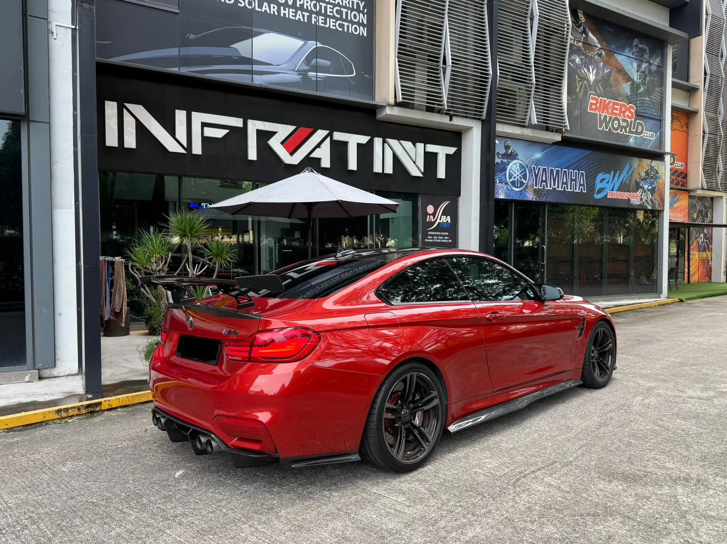 Tinted red BMW M4 rear three-quarter view with carbon wing at Infratint Singapore