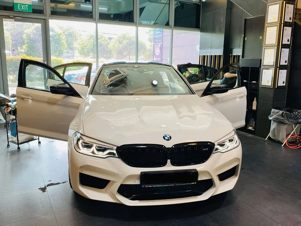 White BMW M5 with doors open during window tinting at Infratint Singapore