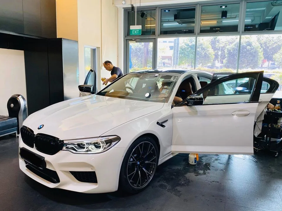 Technician tinting the windscreen of a white BMW M5 at Infratint Singapore
